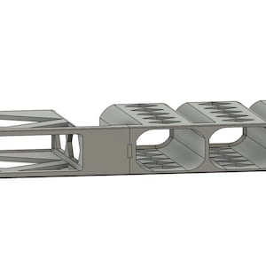 Könnte beinhalten: Ein hellgraues, rechteckiges Objekt mit geometrischem Design. Es verfügt über eine käfigartige Struktur auf der linken Seite und vier zylindrische Fächer auf der rechten Seite. Das Objekt scheint aus einem festen Material zu bestehen, möglicherweise Metall oder Kunststoff.