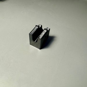 Może przedstawiać: Czarny plastikowy uchwyt wydrukowany w 3D z otworem w kształcie litery U.