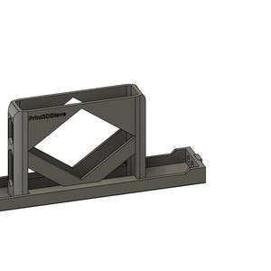 以下が含まれることがあります： 長方形のベースとひし形の開口部を備えた、グレーの3Dプリントオブジェクト。オブジェクトには「Print3DStore」のテキストが表示された垂直の長方形部分があります。デザインにはベースに小さなトレイが含まれています。