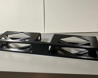 May include: A black metal rack with two open compartments, designed to hold electronic equipment. The rack has a rectangular shape and a textured finish.