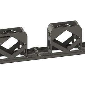 May include: A black metal stand with two open rectangular compartments. The stand is designed to hold two objects, such as reels of cable or other cylindrical items.