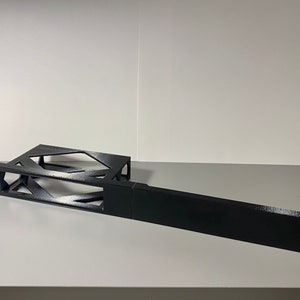 May include: Black metal rack with a geometric design. The rack is made of two pieces, one with a rectangular shape and the other with a more intricate design. The rack is designed to hold electronic equipment.