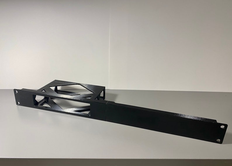 May include: Black metal rack with a geometric design. The rack is made of two pieces, one with a rectangular shape and the other with a more intricate design. The rack is designed to hold electronic equipment.