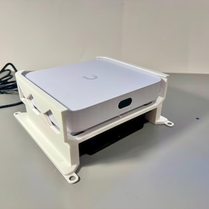 May include: White plastic stand with a white device on top. The device has a U logo on the top.