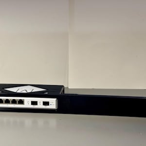 May include: A black metal rack with a white network switch attached. The switch has five ports and a white label with the letter "A" on it.