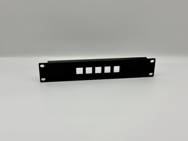 May include: A black metal rack panel with four square cutouts and two mounting holes. The panel is rectangular and designed for mounting in a standard equipment rack. The finish is matte black.