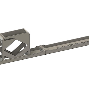 Peut inclure: Un objet imprimé en 3D de couleur gris clair, avec une base rectangulaire et une structure angulaire à côtés ouverts. Le texte "Print2DStore" est visible sur la base. L'objet semble être un outil ou un support.
