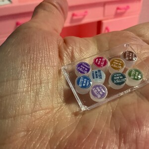 May include: A clear rectangular plastic tray containing eight miniature round containers. Each container features a colored lid with the text Bitsy Bling printed on it. The colors include purple, pink, gold, brown, blue, white, teal, and green.