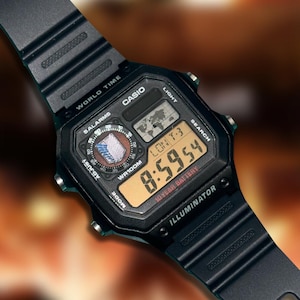 Op de afbeelding: Een zwart Casio digitaal horloge met een kunststof band, voorzien van een vierkante wijzerplaat met een wereldkaart, meerdere alarmfuncties en een 10-jarige batterijindicator. Het scherm toont 8:59:54, LON T-3, WORLD TIME en ILLUMINATOR.