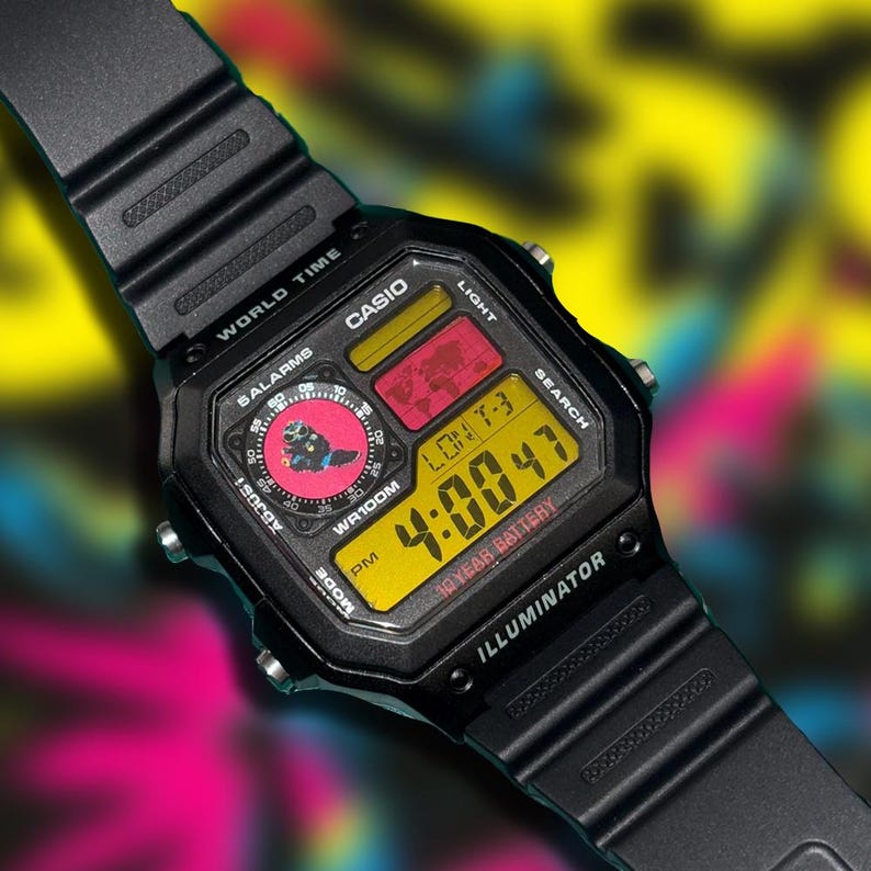 Peut inclure: Montre num&eacute;rique Casio noire avec un affichage num&eacute;rique jaune indiquant l'heure 4:00:47. Le cadran de la montre a des accents rouges et jaunes, et le bracelet est noir. La montre porte l'inscription "CASIO" et "ILLUMINATOR".