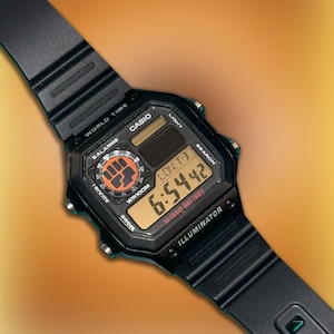 Könnte beinhalten: Schwarze digitale Casio-Uhr mit rechteckigem Zifferblatt und schwarzem Armband. Das Zifferblatt zeigt Uhrzeit, Datum und andere Funktionen an. Die Uhr trägt die Aufschrift "CASIO", "ILLUMINATOR" und "10 YEAR BATTERY". Sie hat auch eine Faust.