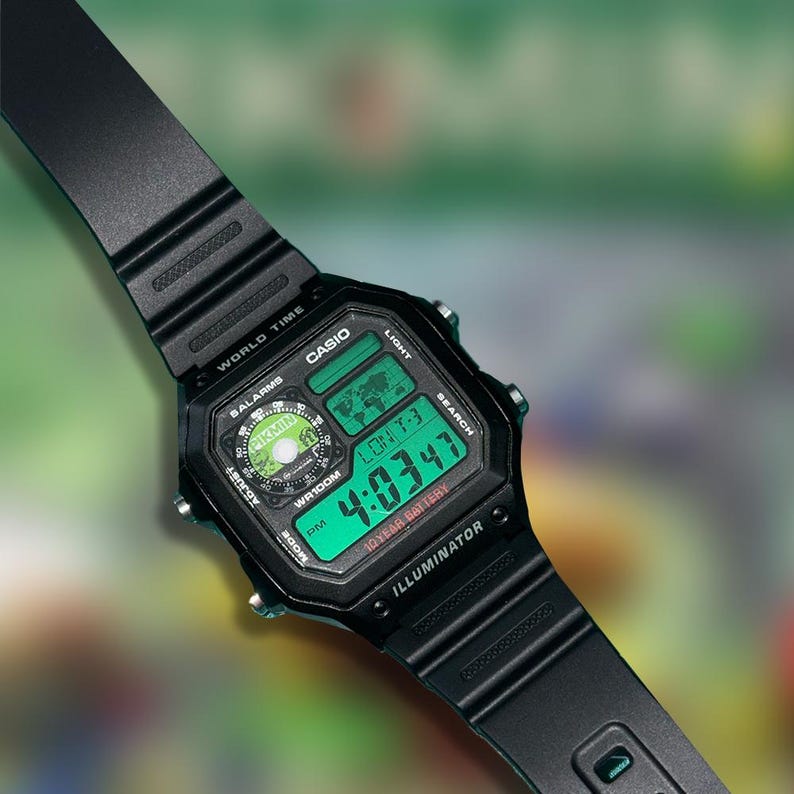 May include: Black Casio digital watch with a rectangular face and a black band. The watch displays the time 4:03:47 in green digits. Features include world time, alarms, and a 10-year battery. The watch has the word "ILLUMINATOR" printed on the face.