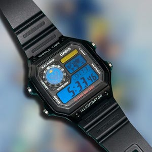 May include: Black Casio digital watch with a blue digital display showing the time 5:33:46. The watch has a black strap and a square face with the text "CASIO", "WORLD TIME", and "ILLUMINATOR". The watch also has a blue and yellow display.