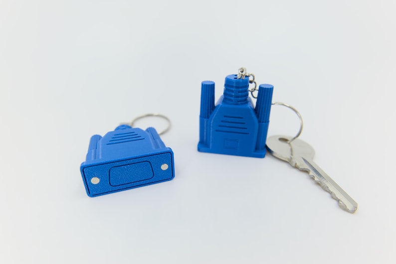May include: Two blue VGA connector keychains with silver key rings and a silver key. The keychains are a bright blue color and have a detailed design. The keychains are on a white background.