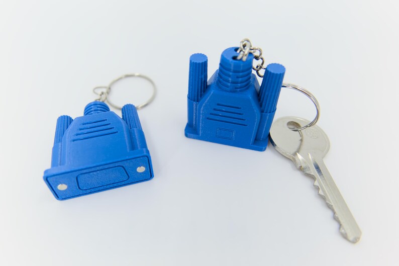 May include: Two blue VGA connector keychains with silver key rings and a silver key. The keychains are a bright blue color and have a detailed design. The keychains are on a white background.