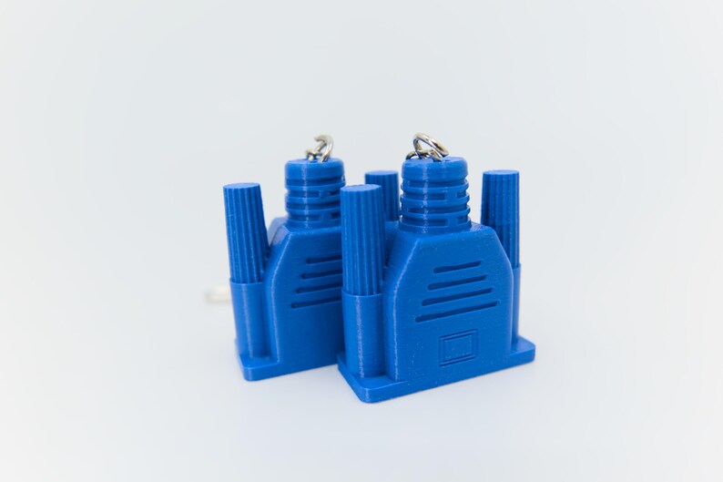 May include: Two blue VGA connectors with silver key rings. The connectors have a rectangular base with a series of parallel lines and cylindrical posts. The background is plain white.
