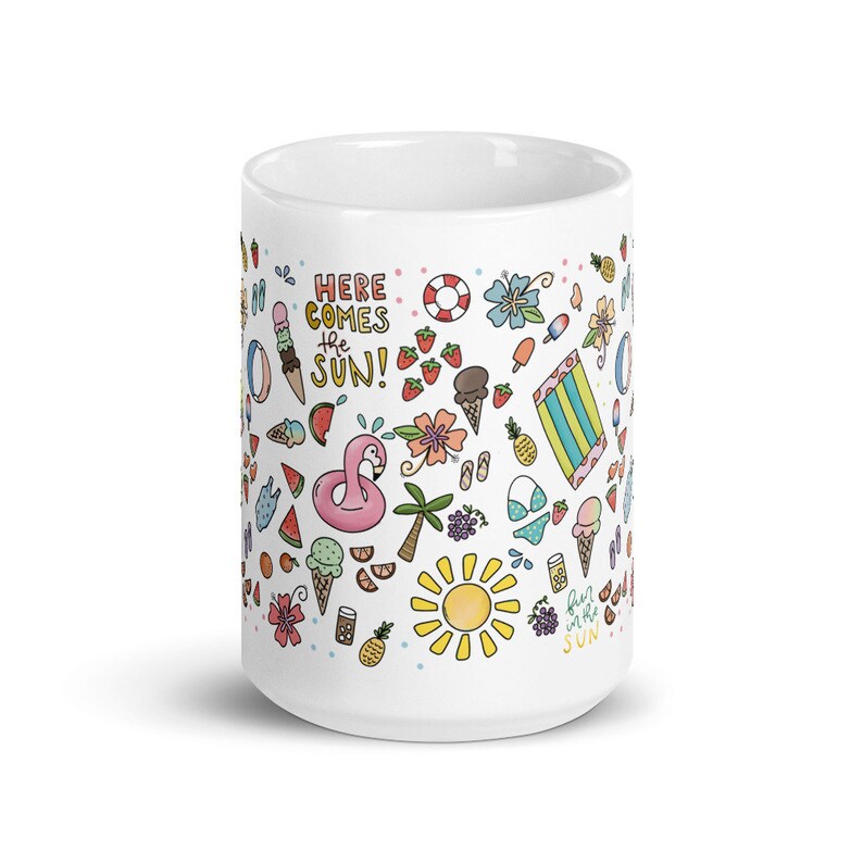 May include: White ceramic mug with a summer-themed design. The mug features a variety of colorful illustrations, including a flamingo float, ice cream cones, watermelon slices, a beach towel, a palm tree, a sun, and the text "Here comes the sun!" and "Fun in the sun".