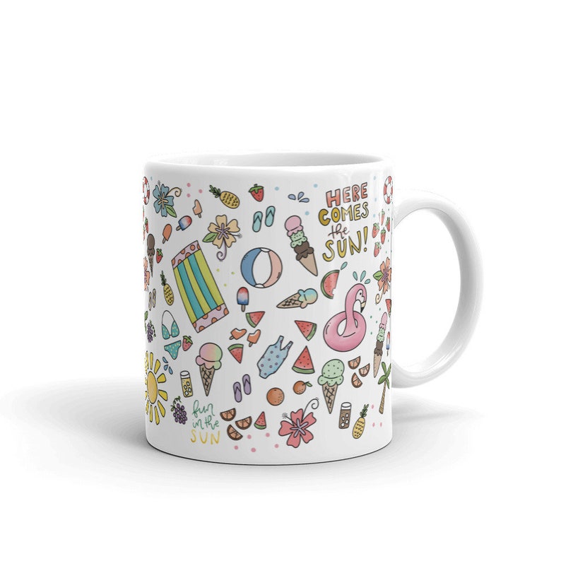 May include: White ceramic mug with a summer-themed design. The mug features a variety of colorful illustrations, including ice cream cones, watermelon slices, flip flops, a flamingo float, and a beach towel. The text "Here comes the sun!" and "Fun in the sun" are also included in the design.