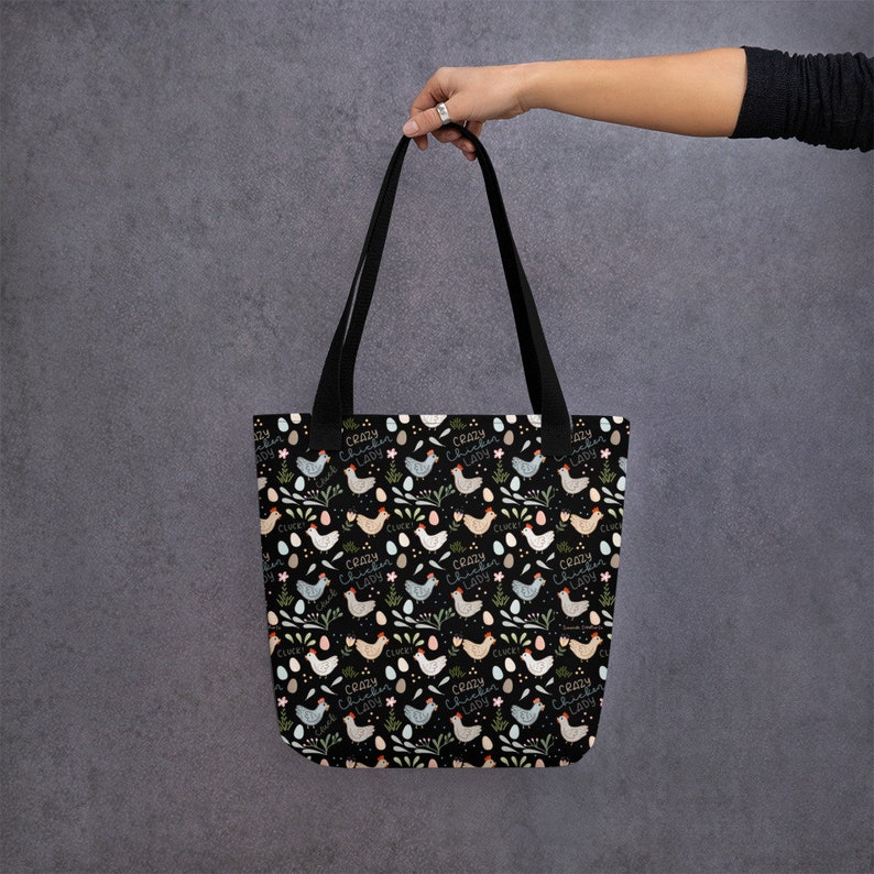 May include: A black tote bag with a repeating pattern of colourful chickens and eggs. The text "Crazy Chicken Lady" is repeated throughout the pattern.