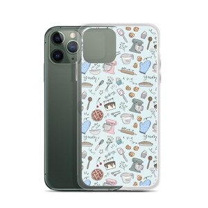 May include: A clear phone case with a light blue background and a pattern of baking-themed illustrations. The illustrations include a mixer, a pie, a cupcake, a rolling pin, a spoon, a cherry, a cake, and the word "yum!" in a handwritten font.