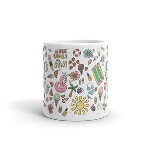 May include: White ceramic mug with a colorful summer-themed design. The mug features a variety of illustrations, including ice cream cones, watermelon slices, pineapples, a flamingo float, a beach towel, and a sun. The text "Here comes the sun!" is written in a playful font.
