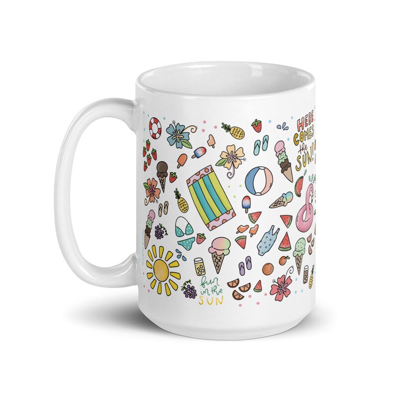 May include: White ceramic mug with a colorful summer-themed design. The design features a variety of summer icons, including ice cream cones, watermelon slices, flip flops, and a sun. The text "Here comes the sun" and "Fun in the sun" are also included in the design.