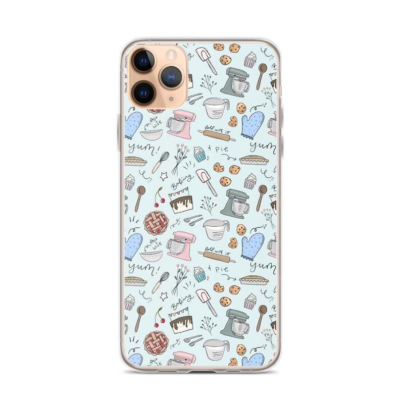 May include: A clear phone case with a light blue background and a repeating pattern of baking-themed illustrations. The illustrations include a mixer, a pie, a cupcake, a cherry, a spoon, a rolling pin, and the words "yum!" and "baking".