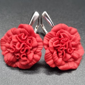 May include: A pair of red carnation flower earrings with silver hooks.