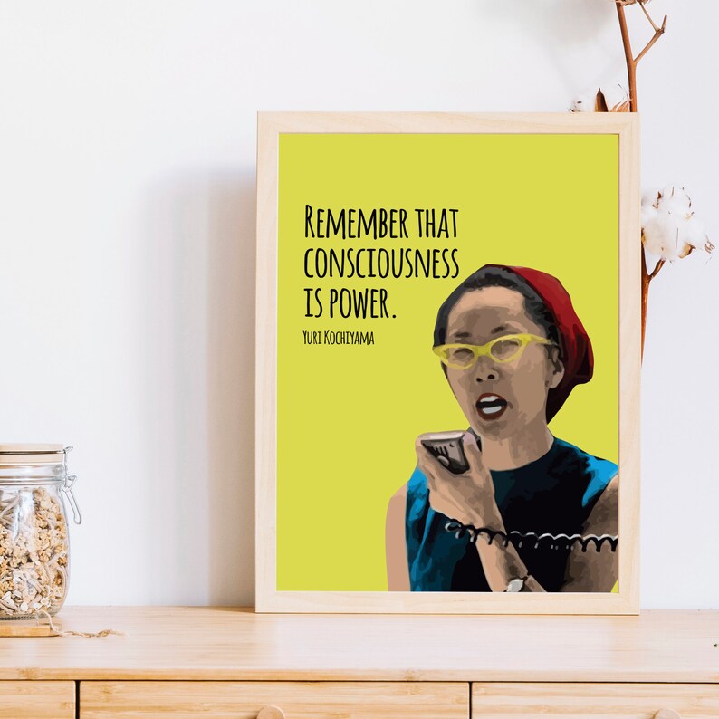 May include: A yellow background with a black and white quote that reads "Remember that consciousness is power."  The quote is attributed to "Yuri Kochiyama".  A woman with a red headband and yellow glasses is speaking into a microphone.