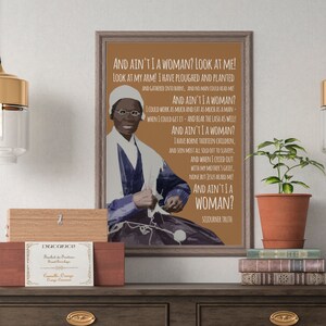 Puede incluir: Un póster enmarcado en marrón con una cita de Sojourner Truth, "And ain't I a woman?" El póster presenta un retrato de Sojourner Truth, una abolicionista y activista por los derechos de las mujeres del siglo XIX.