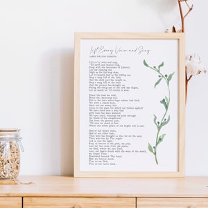 May include: A framed print of the song "Lift Every Voice and Sing" by James Weldon Johnson. The lyrics are printed in black ink on white paper. The frame is a light wood color. A green leafy branch is illustrated in the background.