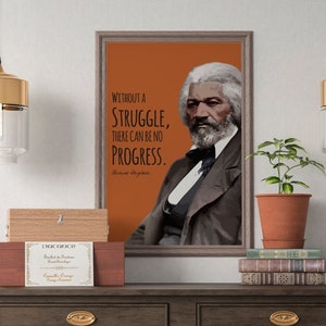 May include: A framed print with an orange background featuring a portrait of Frederick Douglass. The quote "Without a struggle, there can be no progress." is printed in black text below the portrait. The quote is attributed to Frederick Douglass.
