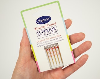 May include: A package of Superior Titanium Coated Topstitch Needles in sizes 70/10, 80/12, 90/14, and 100/16. The package is labeled for quilting, appliqué, and embroidery.