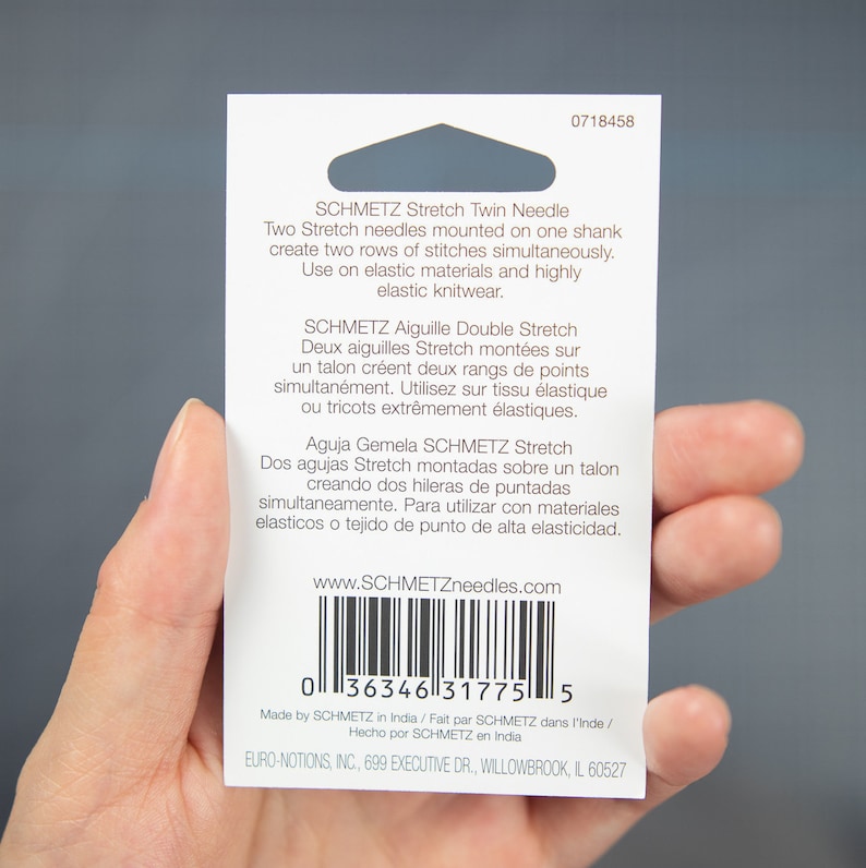 Peut inclure: Une carte blanche avec du texte noir d&eacute;crivant l'aiguille double extensible SCHMETZ et l'aiguille double extensible SCHMETZ. La carte comprend &eacute;galement un code-barres et l'adresse du site Web www.SCHMETZneedles.com.