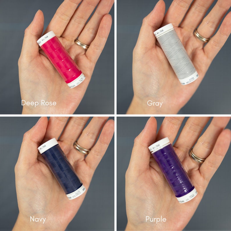 May include: Four spools of thread in different colors: deep rose, gray, navy, and purple. Each spool is held in a hand.