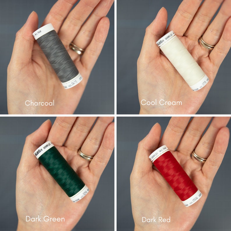 May include: Four spools of thread in different colors: charcoal, cool cream, dark green, and dark red. Each spool is labeled with the brand name " G&uuml;termann" and a color number.