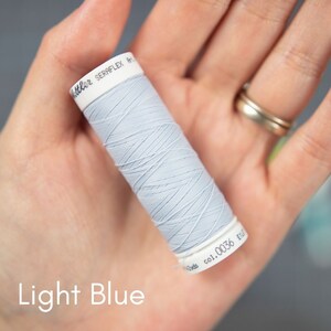 May include: A spool of light blue thread with the text "SERRAFLEX Art. 0036 E.U." on the label.