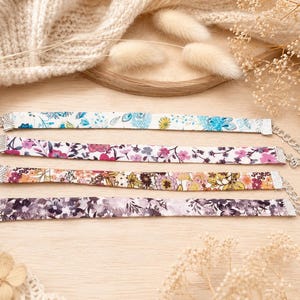 Peut inclure: Quatre ras-de-cou en tissu ornés de motifs floraux dans les tons bleu, rose, jaune et violet. Chaque collier dispose d'embouts en métal argenté, d'un fermoir mousqueton et d'une chaînette d'extension réglable pour le cou.