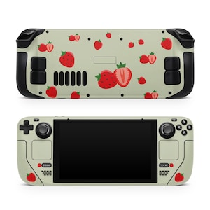 May include: A green and black handheld gaming device with a screen displaying a black background. The device has a red and white strawberry pattern on the back and front.