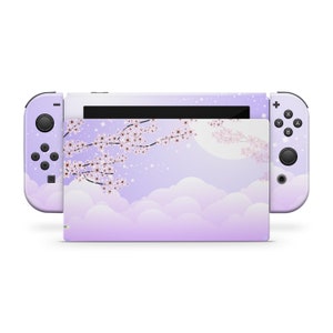 May include: A purple and white Nintendo Switch console skin with a design of a cherry blossom branch, clouds, and a moon. The skin is designed to fit the Nintendo Switch console and Joy-Cons.