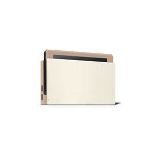 Pu&ograve; includere: Una console Nintendo Switch beige con una custodia protettiva bianca. La console &egrave; chiusa e lo schermo non &egrave; visibile.