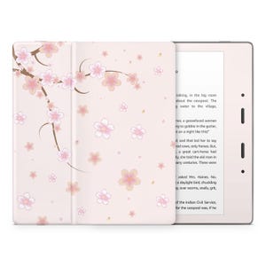 May include: A pink and white e-reader case with a floral design. The case features a cherry blossom pattern with pink flowers and brown branches. The e-reader is open to a page of text.