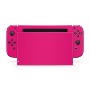 May include: A pink Nintendo Switch console with black buttons and a black screen. The console is closed and the Joy-Con controllers are attached.