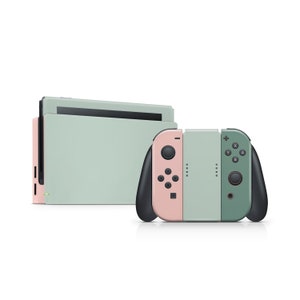May include: A green, pink, and gray Nintendo Switch console with two controllers. The console is in the background and the controllers are in the foreground.
