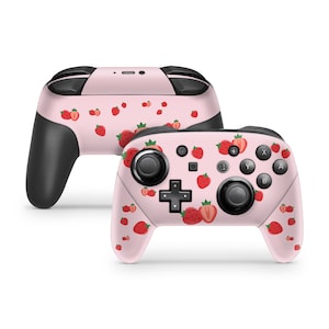 May include: A pink Nintendo Switch controller with a strawberry pattern. The controller has a black grip and buttons.