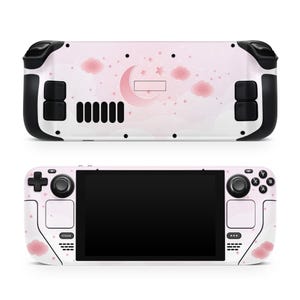 May include: A pink and white gaming console with a moon and clouds design. The console has a black screen and black buttons.