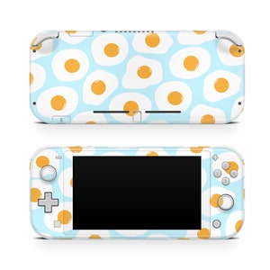 May include: A white Nintendo Switch Lite console with a blue and white pattern of fried eggs. The console has a black screen and white buttons.