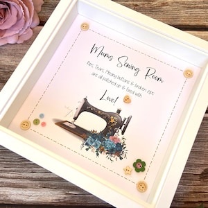 May include: White frame with a sewing machine illustration and the text "Mums Sewing Room Rips, Tears, Missing buttons & broken zips are all patched up & fixed with Love!" surrounded by decorative buttons.
