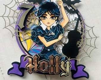 May include: A cake topper with a cartoon girl in a black dress, a black violin, bats, and a spiderweb design. The number 7 and the name "Holly" are included. The topper is primarily purple, black, and silver.