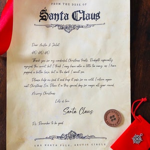 May include: A vintage-style letter from Santa Claus to Austin and Juliet. The letter is written on parchment paper and has a red ribbon tied around it. The letter includes a message from Santa Claus, thanking them for their Christmas treats and asking them to keep a lost button safe for him. The letter is signed "Santa Claus" and includes the address "The North Pole, Arctic Circle".